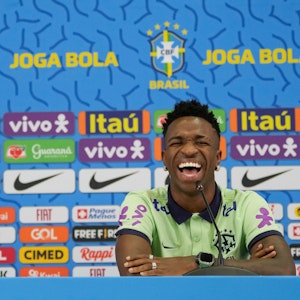 Brasilien-Nationalspieler Vinicius Junior lacht über Katze auf dem Tisch.