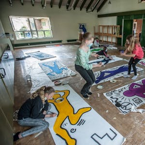 Sechs Kinder arbeiten an Kunstwerken, die auf dem Boden der Evangelischen Kirche in Hilgen ausgelegt sind.