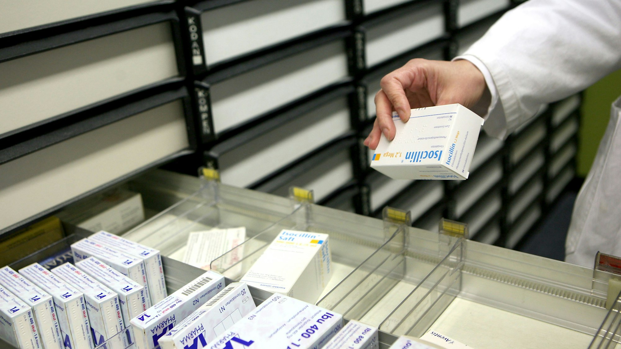 Eine Apothekerin nimmt in einer Apotheke in Köln ein Medikament aus dem Schrank.