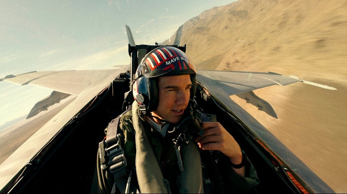 Tom Cruise als Captain Pete „Maverick“ Mitchell in „Top Gun: Maverick“. Er sitz in einem Flieger und spricht in ein Mikrofon an seiner Kleidung.