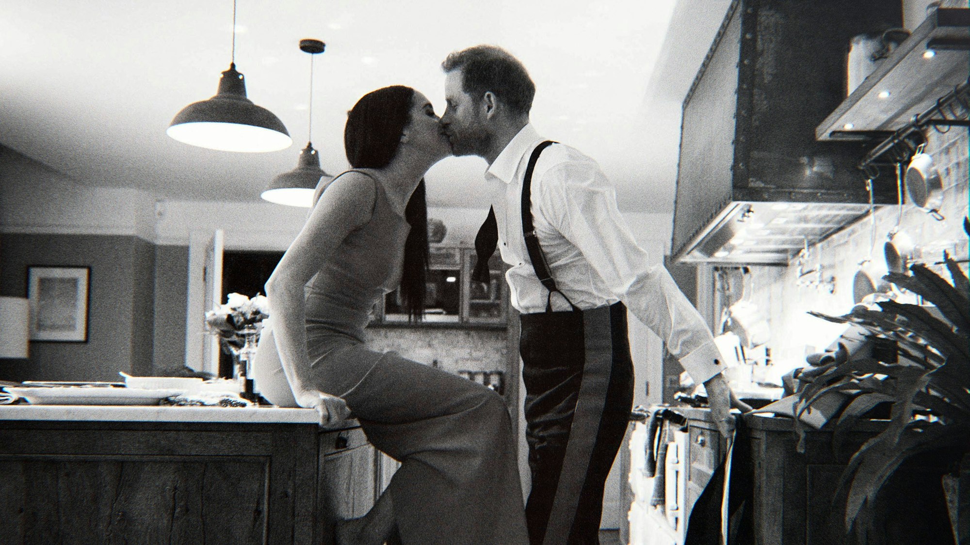 Prinz Harry und Herzogin Meghan küssen einander in einer Küche.