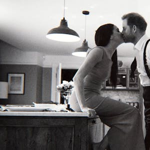 Prinz Harry und Herzogin Meghan küssen einander in einer Küche.