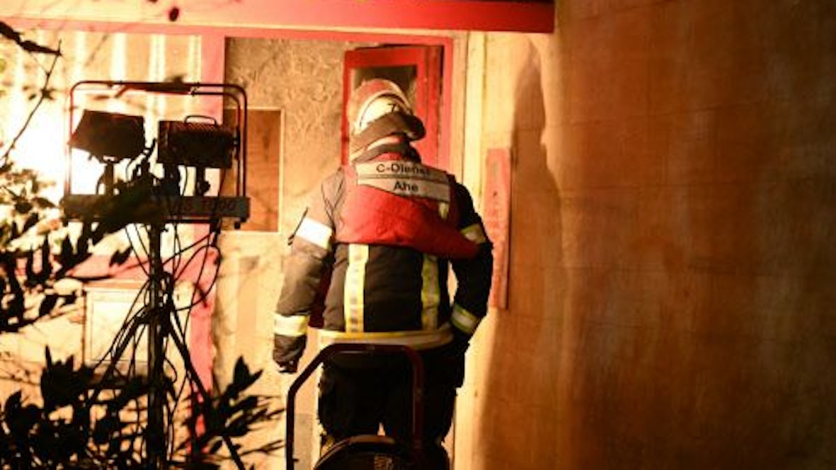 Ein Feuerwehrmann betritt das Hochhaus, in dem es gebrannt hat. Starke Scheinwerfer erleichtern ihm die Arbeit