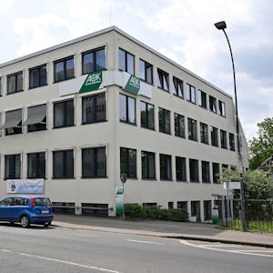 Das dreigeschossige AOK-Gebäude mit drei Autos davor an der Bensberger Straße.
