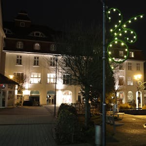 Auf dem dunklen Rathausplatz in Bergneustadt leuchtet eine Lichterkette an einem Laternenmast.