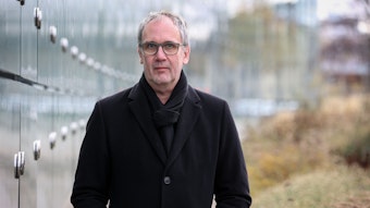 Bestseller-Autor Volker Kutscher steht in einem schwarzen Mantel vor dem Neven-DuMont-Haus