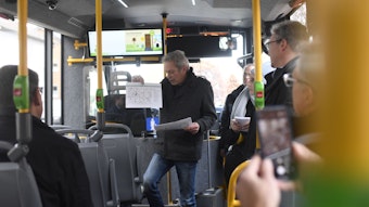 Andreas Glodowski steht in einem Kleinbus und hält einen ausgedruckten Fahrplan hoch, während er das neue Zülpicher ÖPNV-Konzept vorstellt.