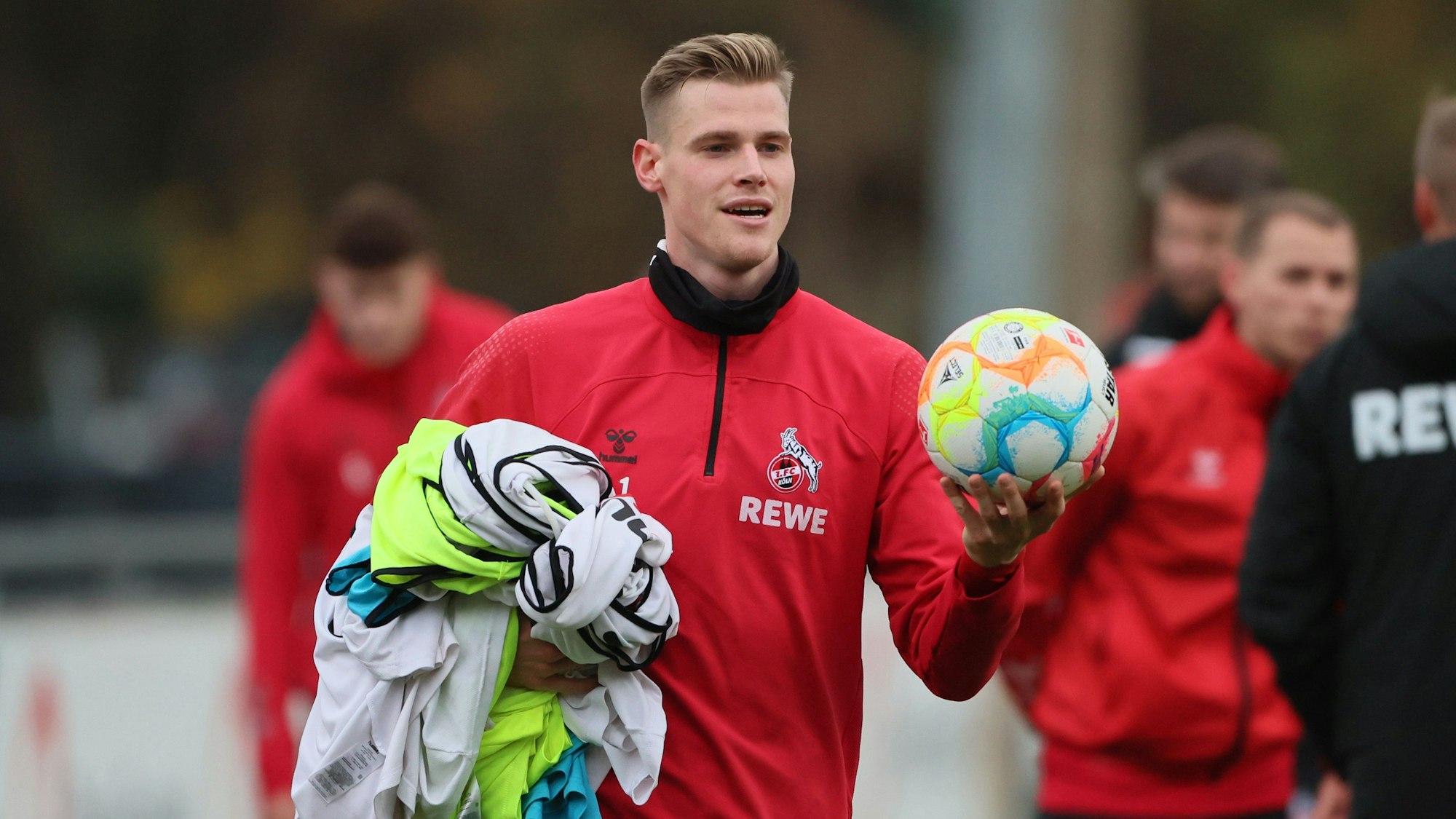 Steffen Tigges trägt beim Training des 1. FC Köln einen Ball und Shirts.