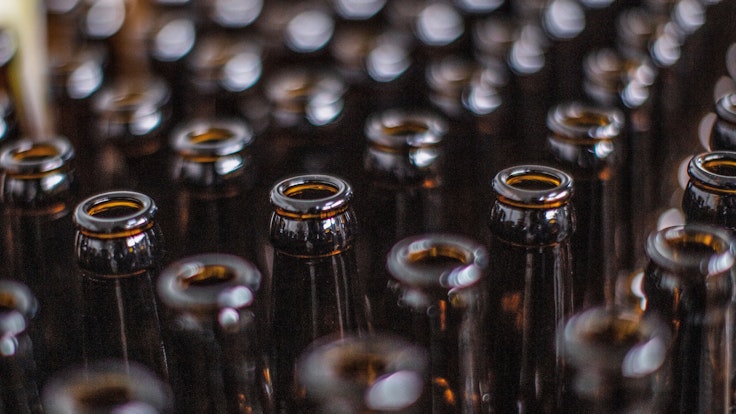 Das Symbolfoto zeigt viele braune Bierflaschen, die nebeneinanderstehen.