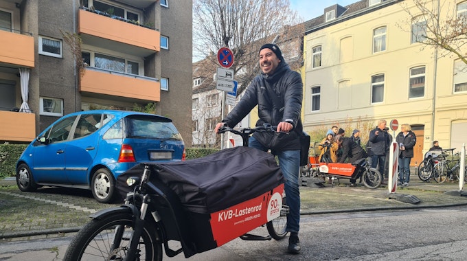 KVB präsentiert in Deutz KVB-Lastenrad als neues Angebot in Köln. Ein Mann sitzt lachend auf dem Rad.
