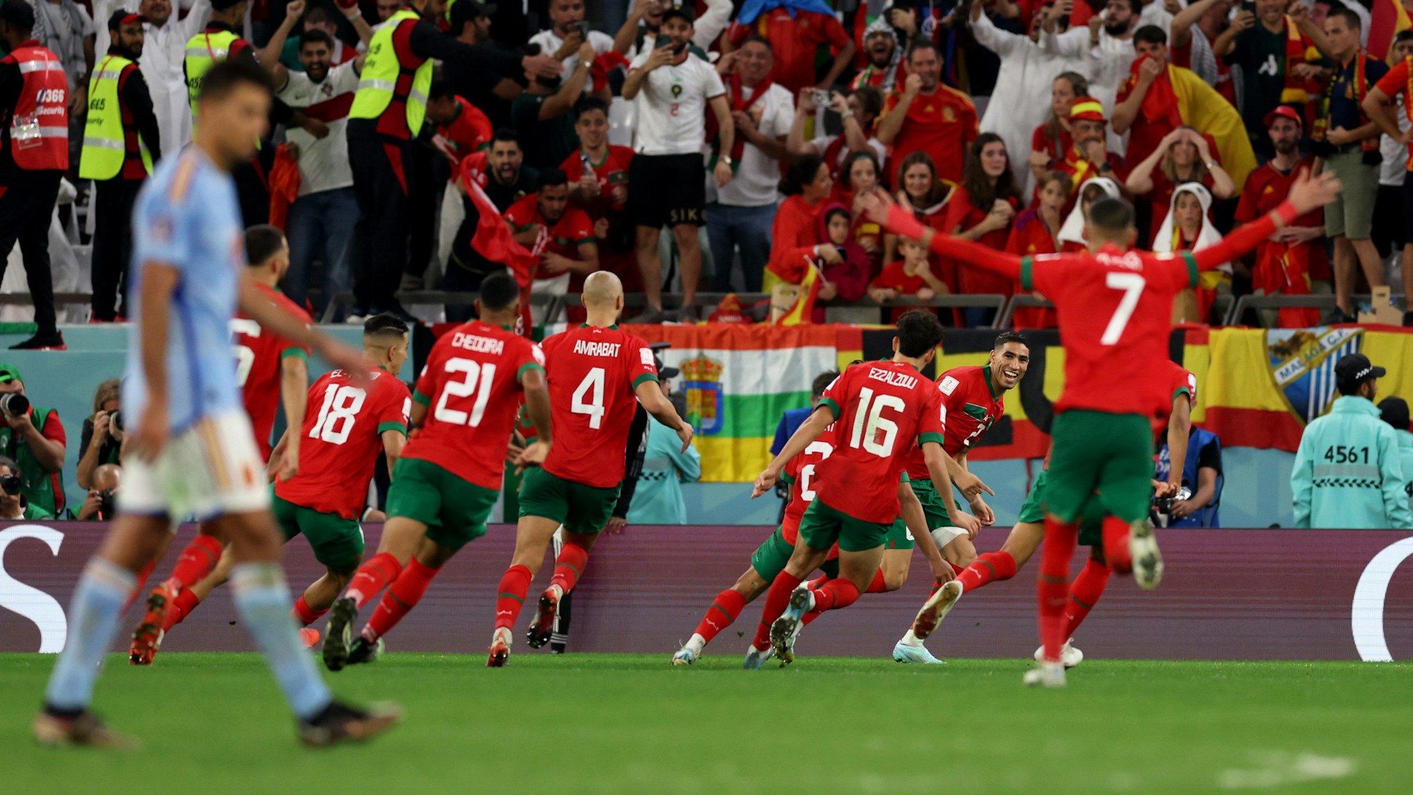 Die Spieler von Marokko jubeln nach dem Sieg im Elfmeterschießen bei der WM 2022. Bei Spanien ist die Enttäuschung groß, wie im Fanblock im Hintergrund zu sehen ist.
