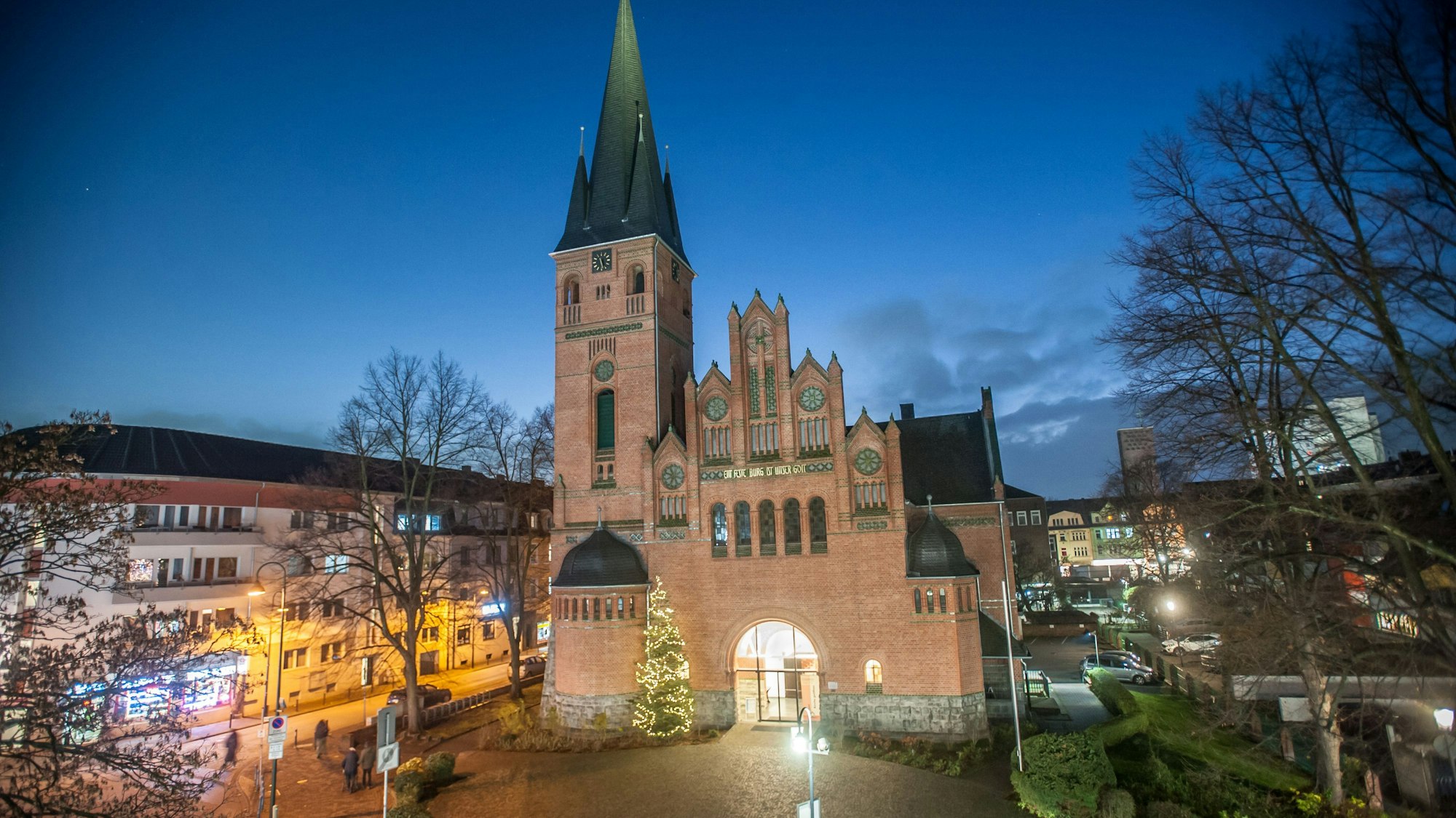 Die evangelische Christuskirche in Wiesdorf. Vor der Kirche steht zur Weihnachtszeit ein geschmücktem Tannenbaum.