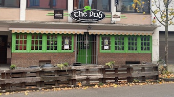 Blick auf die Fassade des The Pub. Die Fensterläden und die Eingangstür sind knallgrün gestrichen.