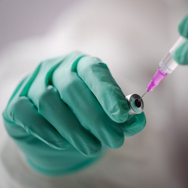 Ein Mitarbeiter in einem Impfzentrum zieht eine Spritze mit dem Impfstoff gegen Covid-19 auf.