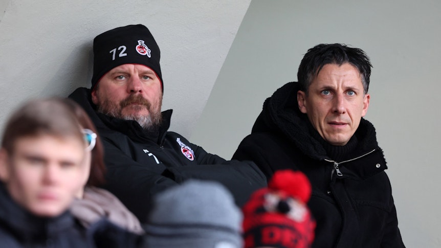 Steffen Baumgart und Christian Keller sitzen nebeneinander auf der Tribüne im Franz-Kremer-Stadion.