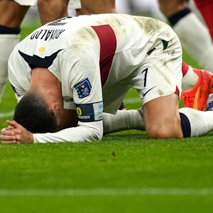 Cristiano Ronaldo hockt auf dem Rasen und hält sich enttäuscht den Kopf.