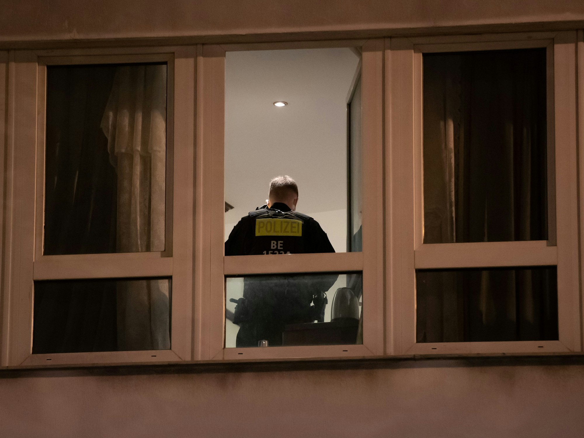 Ein Polizist steht in einem Zimmer eines Hotels und durchsucht es.