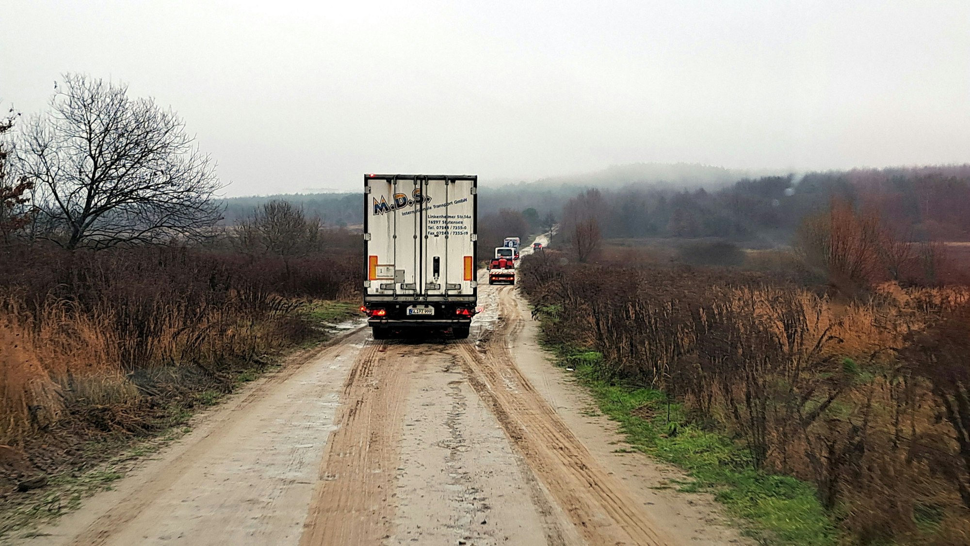 Ein Lkw fährt auf einem braunen Weg in der ukrainischen Landschaft.