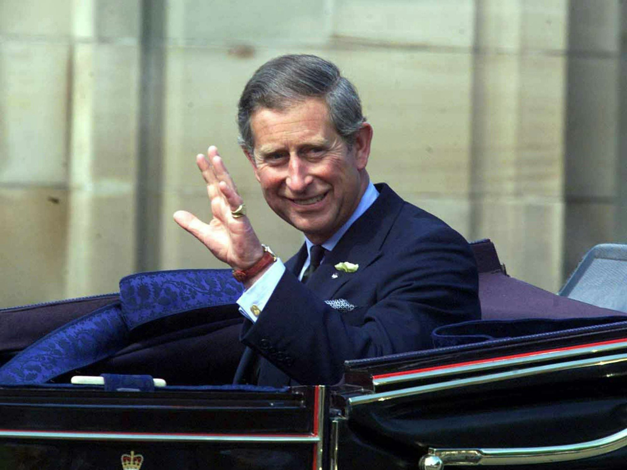 Prinz Charles winkt im Auto sitzend der Menge zu.