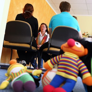 Eine Familie nimmt in einer Beratungsstelle k an einer Erziehungsberatung mit Psychologin Birgit Höppner teil. Im Vordergrund liegen Plüschfiguren aus der Sesamstraße