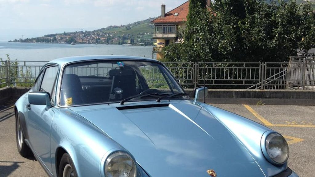 Ein blauer Porsche steht auf einem Parkplatz.
