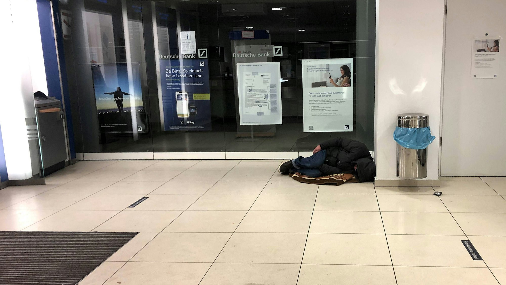 Obdachloser schläft im Vorraum nachts in einer Filiale der deutschen Bank