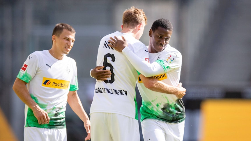 Mamadou Doucouré und Christoph Kramer von Borussia Mönchengladbach umarmen sich nach dem Spiel gegen Union Berlin. Stefan Lainer steht neben den beiden Spielern.