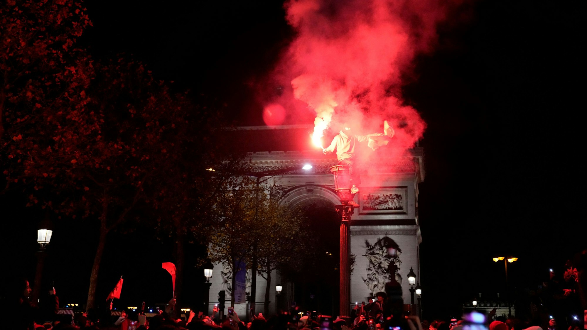 Marokko-Fans jubeln auf den Straßen von Paris über den Einzug ins WM-Halbfinale, zünden dabei Pyrotechnik.