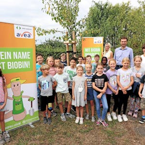 Kinder haben sich im Hitdorfer Kleingarten vor Plakaten mit dem Biotonnen-Maskottchen Biobin aufgestellt.