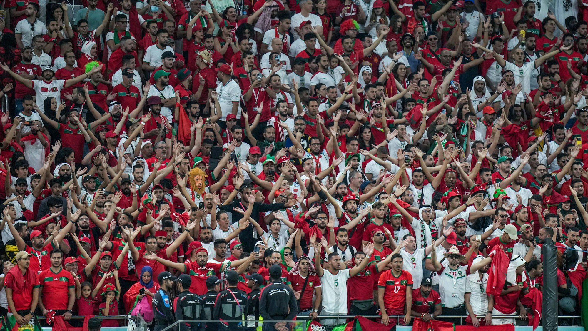 Man sieht viele Personen in weiß-roter Kleidung auf einer Fußballtribüne.