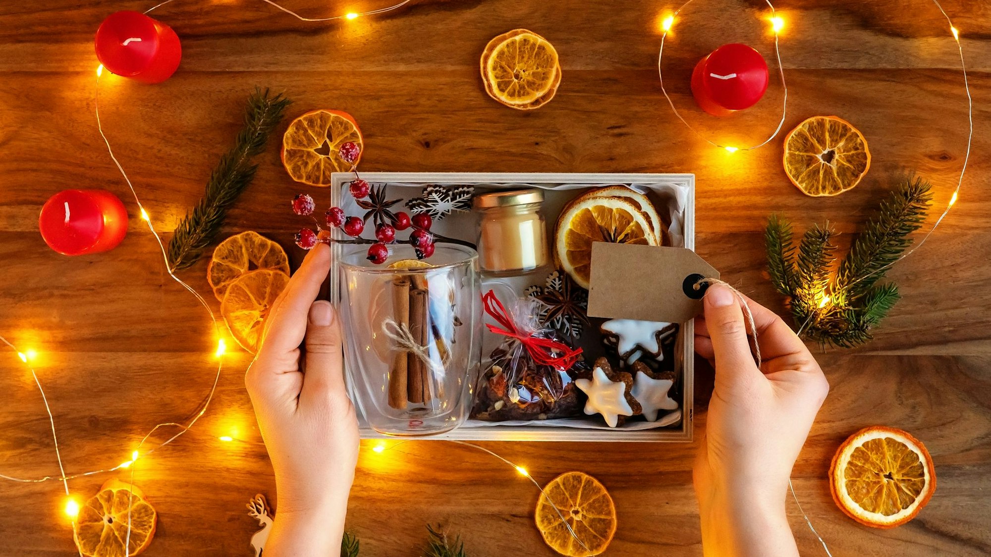 Auf dem Foto sieht man eine kleine Geschenkbox mit Orangenschalen, Keksen und Zimtstangen u.ä. darin.