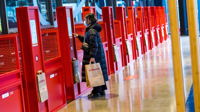 Eine Kundin lässt sich in Rotterdam ihren QR-Code in einer roten Abholstelle des chinesischen Supermarkts Ochama scannen.