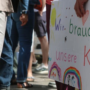 Eltern und Kinder der Evangelischen Kita in Zollstock demonstrieren mit Schildern gegen die geplante Schließung der Einrichtung.