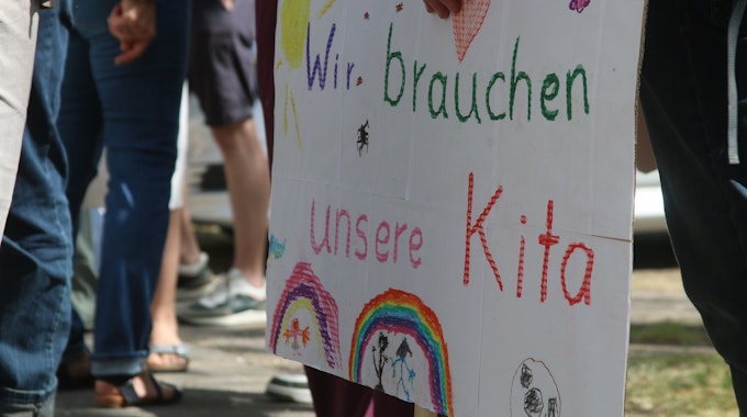 Eltern und Kinder der Evangelischen Kita in Zollstock demonstrieren mit Schildern gegen die geplante Schließung der Einrichtung.