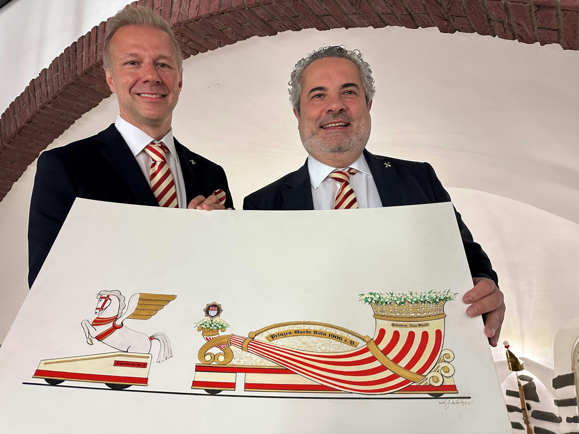 Marcus Gottschalk und Dino Massi zeigen einen Entwurf für den neuen Präsidentenwagen der Prinzen-Garde für den Rosenmontagszug 2023.