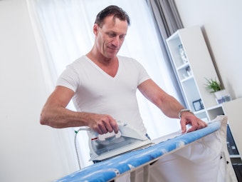 Ein Mann beim Bügeln eines Hemdes.