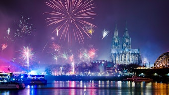 Feuerwerk am Nachthimmel von Köln. Im Hintergrund der Kölner Dom, davor die Hohenzollernbrücke.