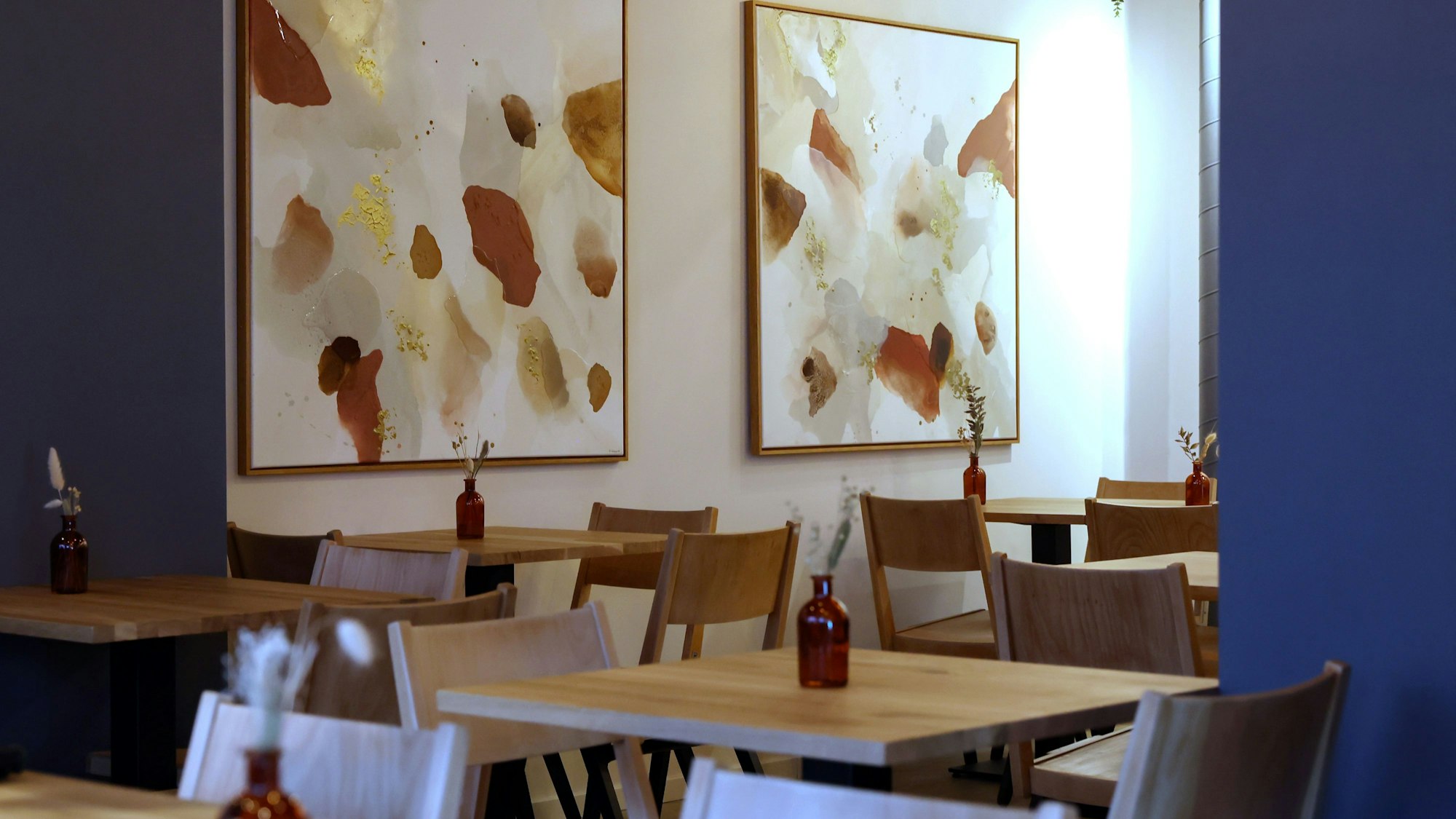 Das Bild zeigt das Innere des Restaurants: Bilder von Natascha Wierny schmücken die Wände.