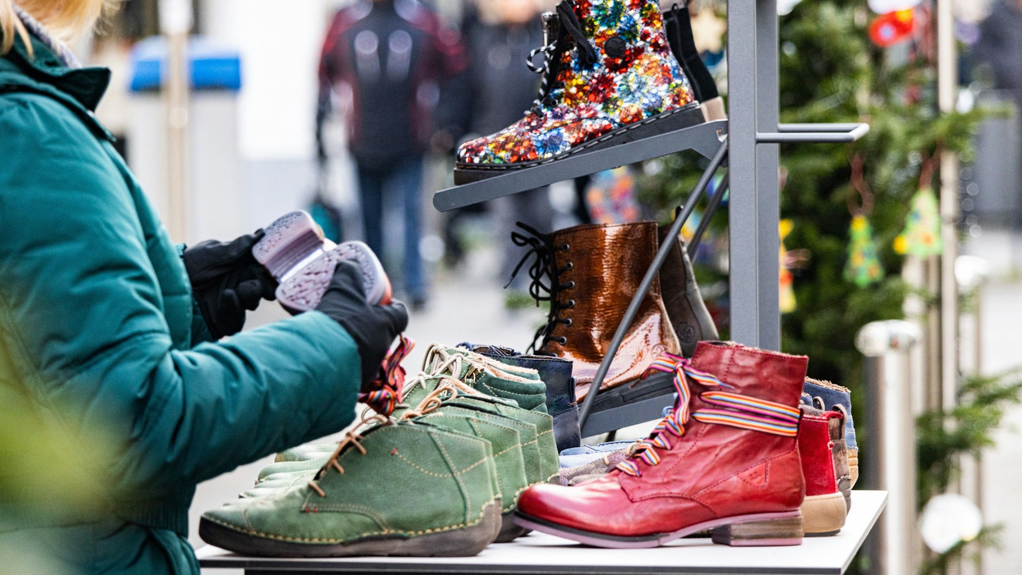 Beim gut besuchten verkaufsoffenen Sonntag am dritten Adventswochenende in Rheinbach schaut sich eine Frau verschiedene Stiefel an.
