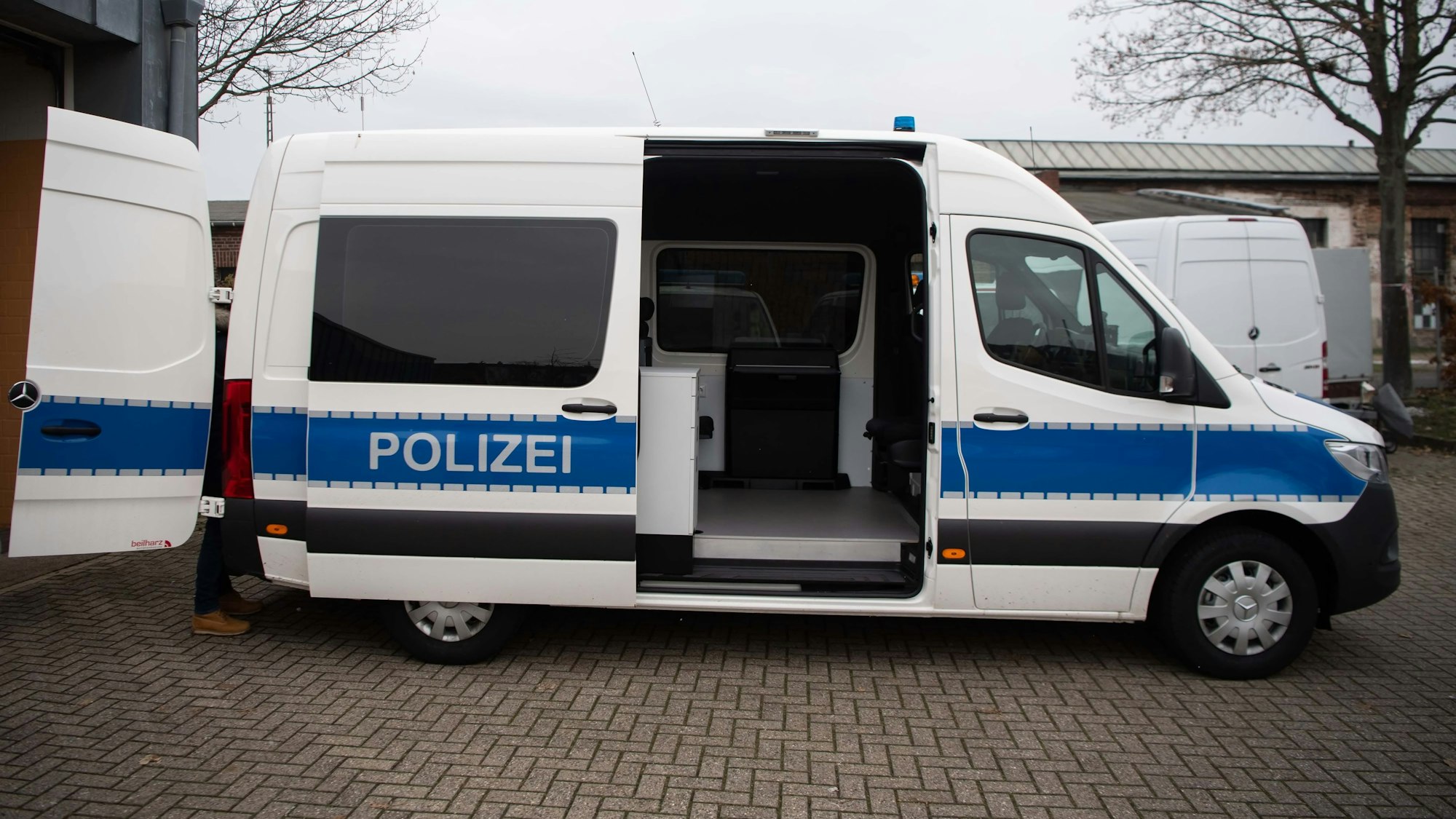 Ein Polizei-Fahrzeug vom Typ Mercedes Sprinter steht mit geöffneter Schiebetür auf einem Parkplatz.