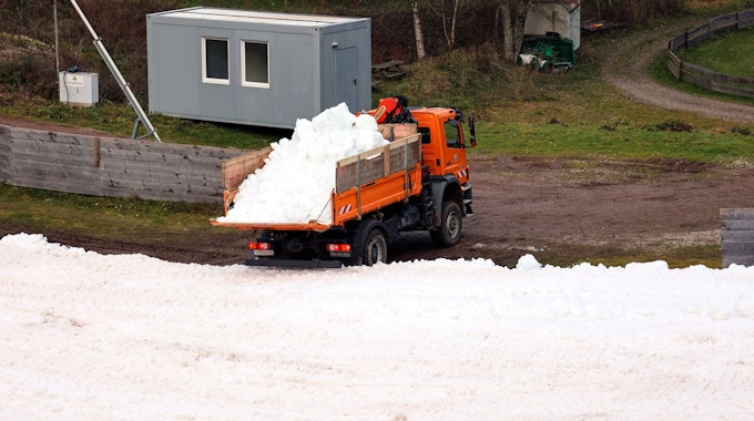 Ein Lastwagen kippt Altschnee in den Schanzenauslauf.