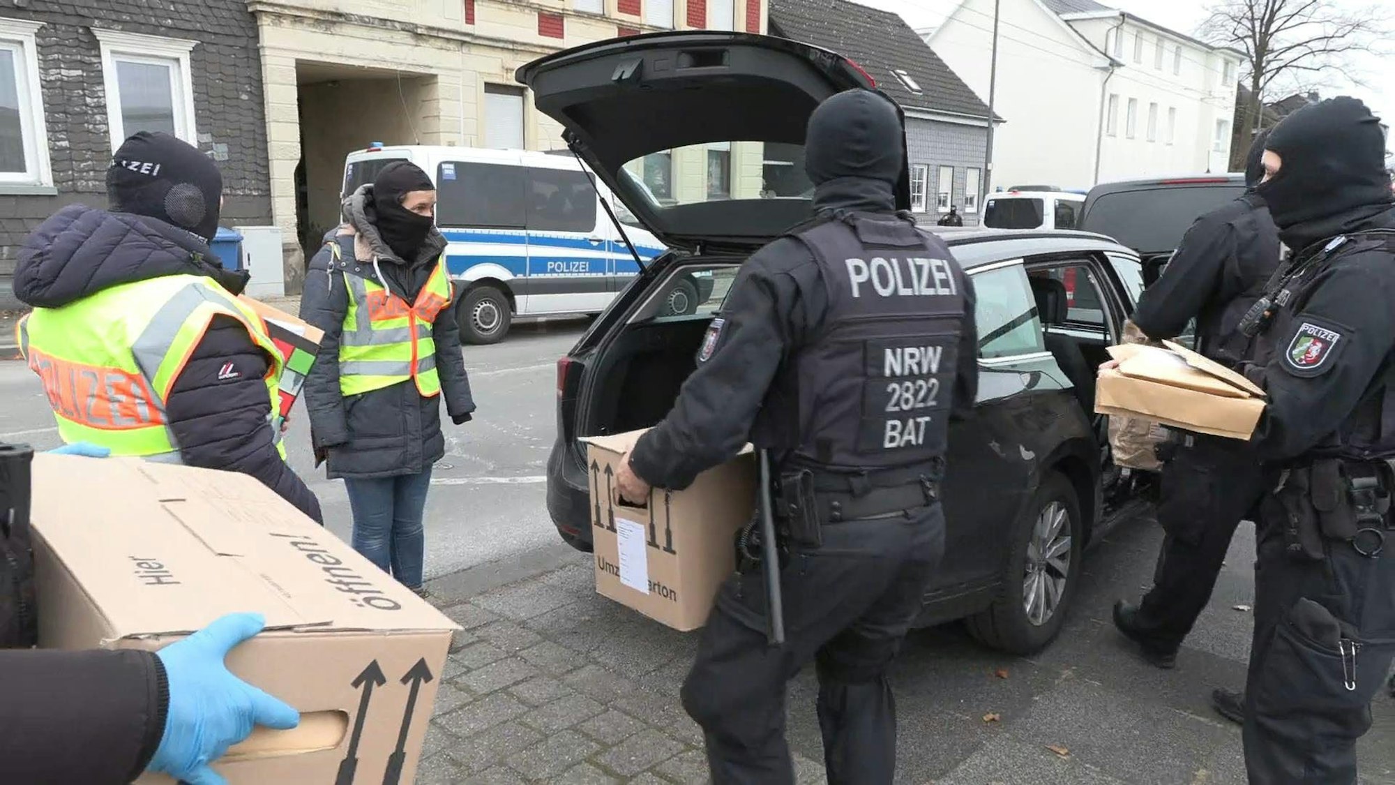 Solingen: Polizisten tragen sichergestellte Beweismittel nach einer groß angelegten Razzia zu ihren Fahrzeugen.