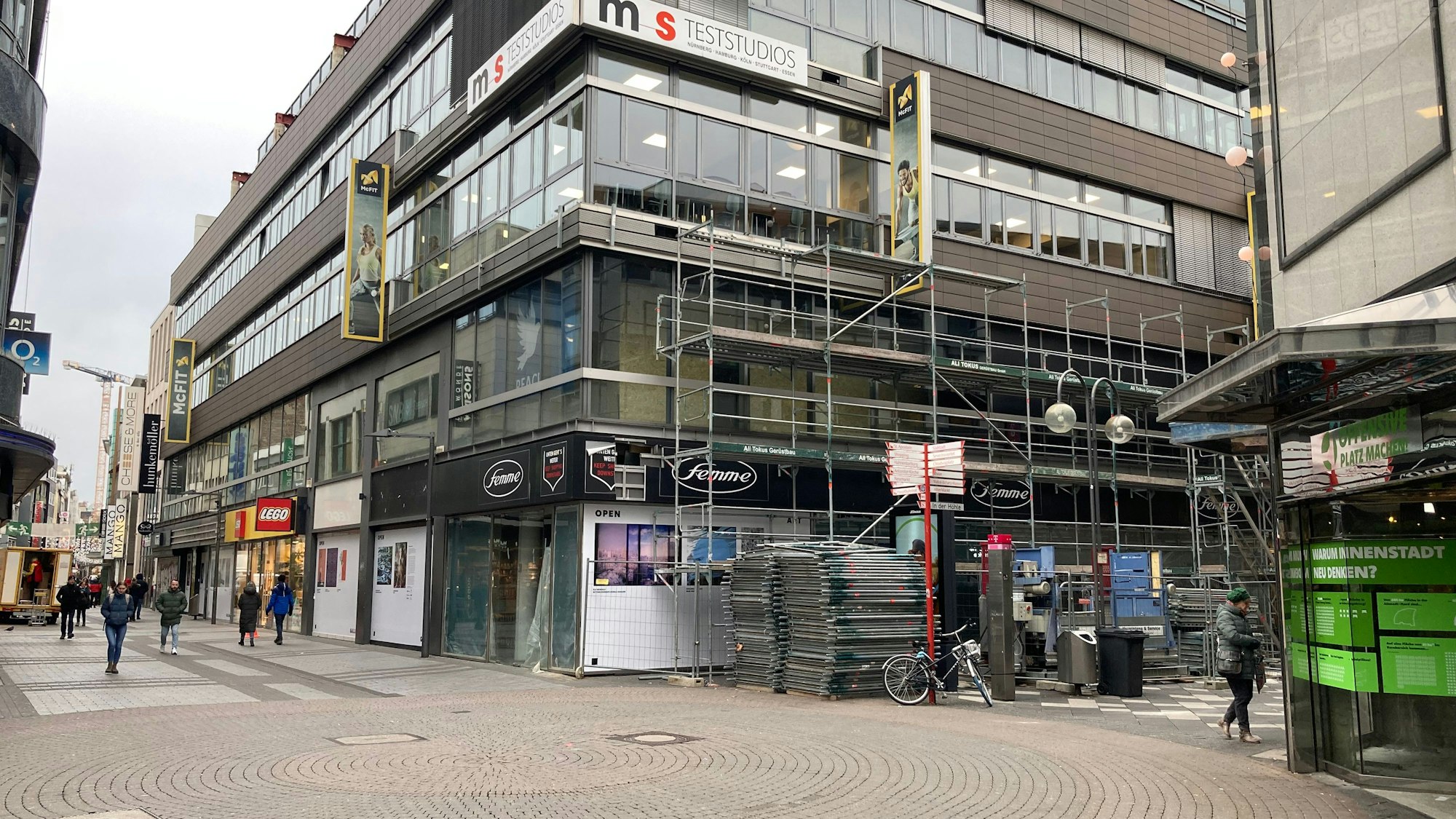Das Bild zeigt ein Geschäftshaus auf der Hohe Straße, Arbeiter errichten gerade ein Baugerüst.