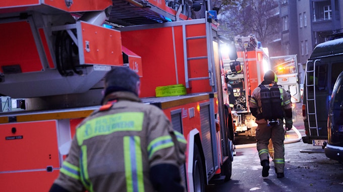 Feuerwehrmänner laufen im Dezember 2022 auf der Schudomerstraße in Neukölln zu den Einsatzfahrzeugen.