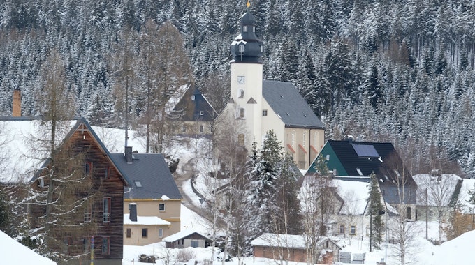 Die Kirche und Häuser von Kühnhaide, einem Ortsteil der sächsischen Stadt Marienberg im Erzgebirgskreis, sind von Schnee umgeben.