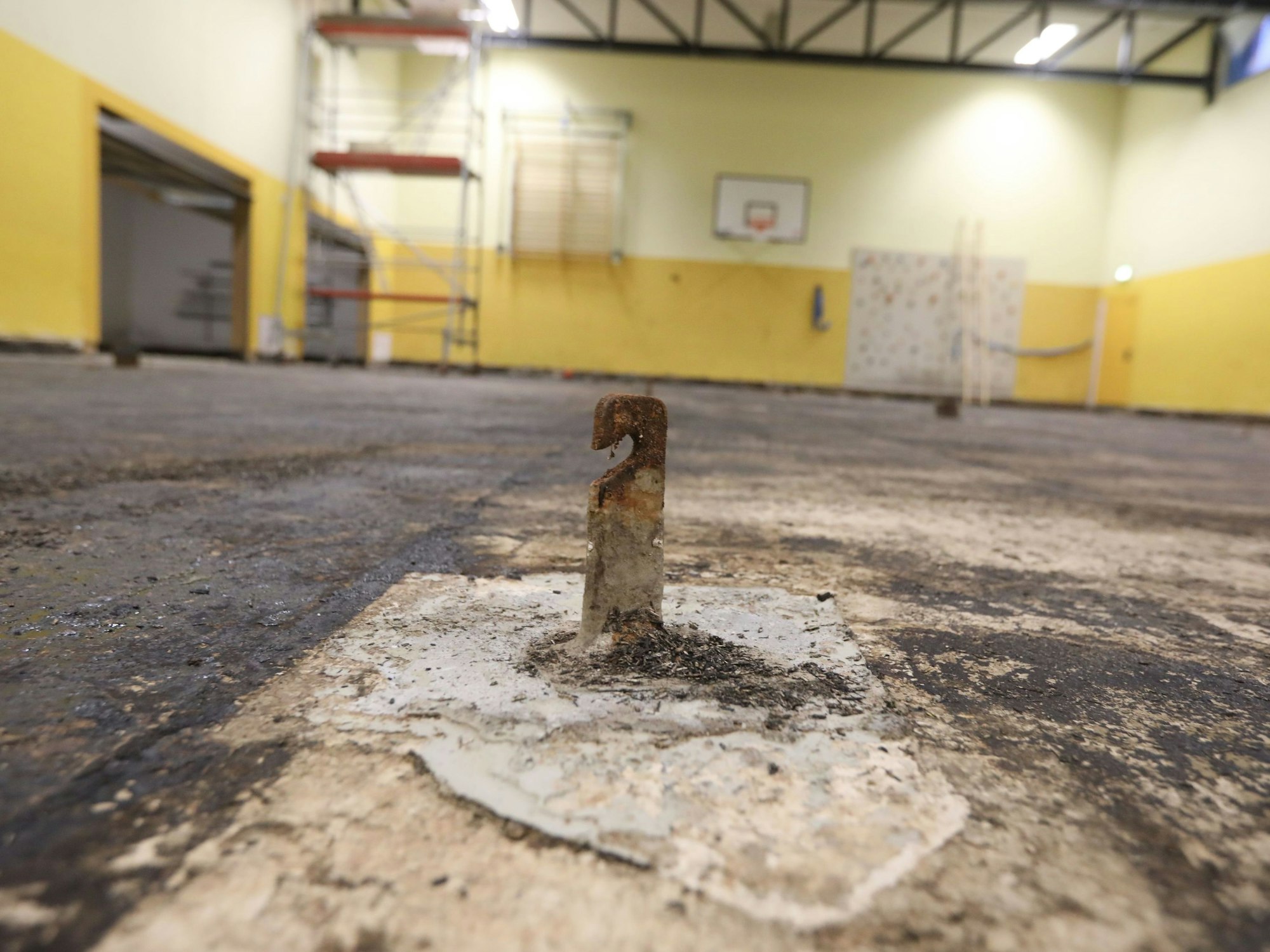 Der nasse Boden der großen Turnhalle an der KGS Kupfergasse ist komplett entfernt worden. Im Vordergrund ein alter Haken im Boden.