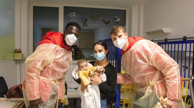 FC-Spieler Kingsley Schindler und Jonas Urbig besuchen Mihriban Burakcin mit dem kleinen Ali Merdan in einem Zimmer der Kinderklinik am Krankenhaus Porz.