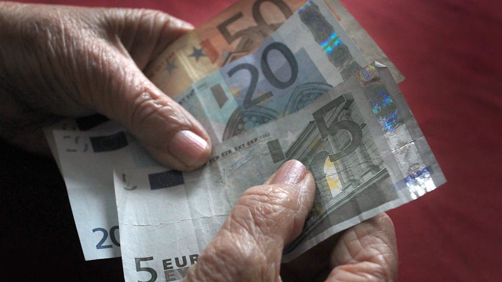 Eine ältere Frau hält verschiedene Euronoten in der Hand.