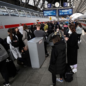 Reisende stehen am Hauptbahnhof und warten auf ihre Weiterfahrt.