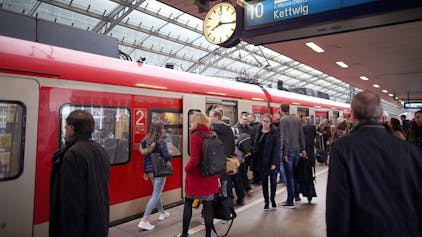 Pendler stehen im Hauptbahnhof Köln vor einer S-Bahn.&nbsp;
